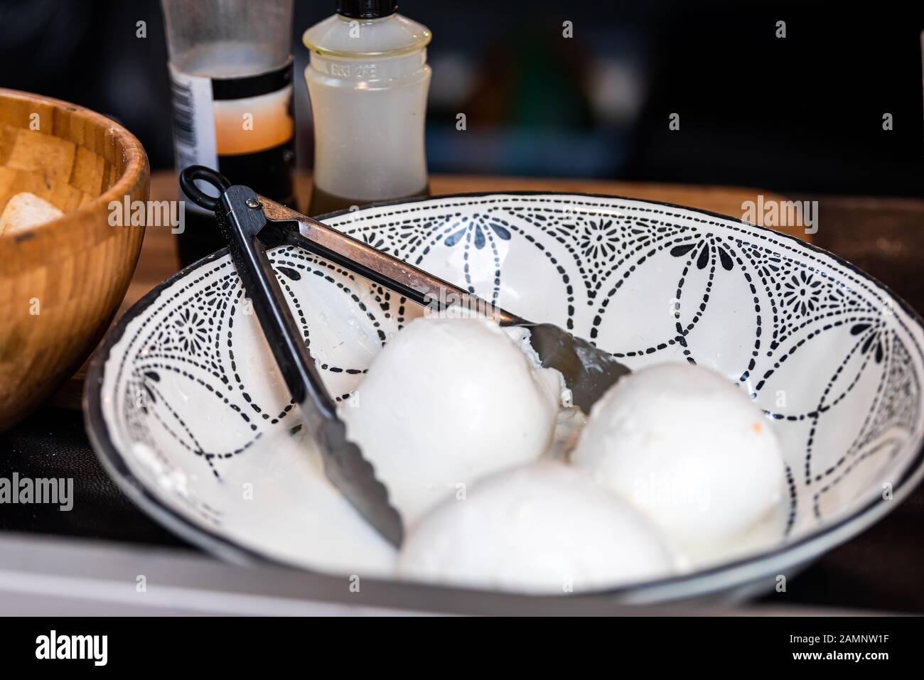 Closeup of mozzarella balls on display in restaurant cafe store street food vendor shop with tongs and white cheese Stock Photo