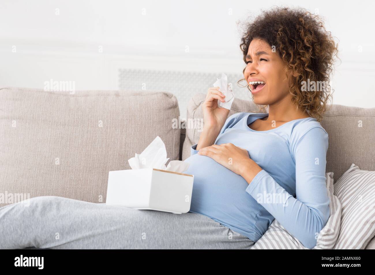 Depression and pregnancy. Expectant woman crying, sitting on sofa Stock Photo
