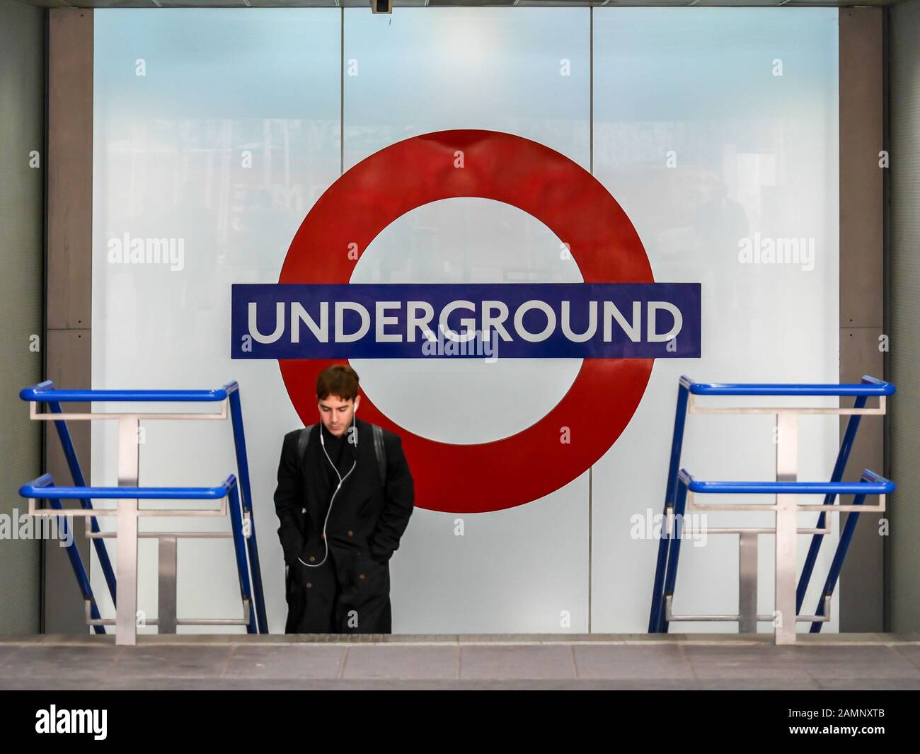 Transport for London. A commuter leaving a London Underground tube train station with the familiar roundel logo in the background. Stock Photo