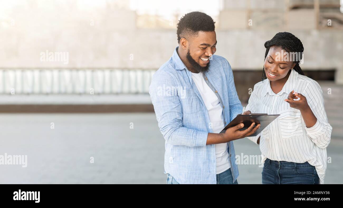 Millennial afro guy answering social survey to female interviewer outdoors Stock Photo