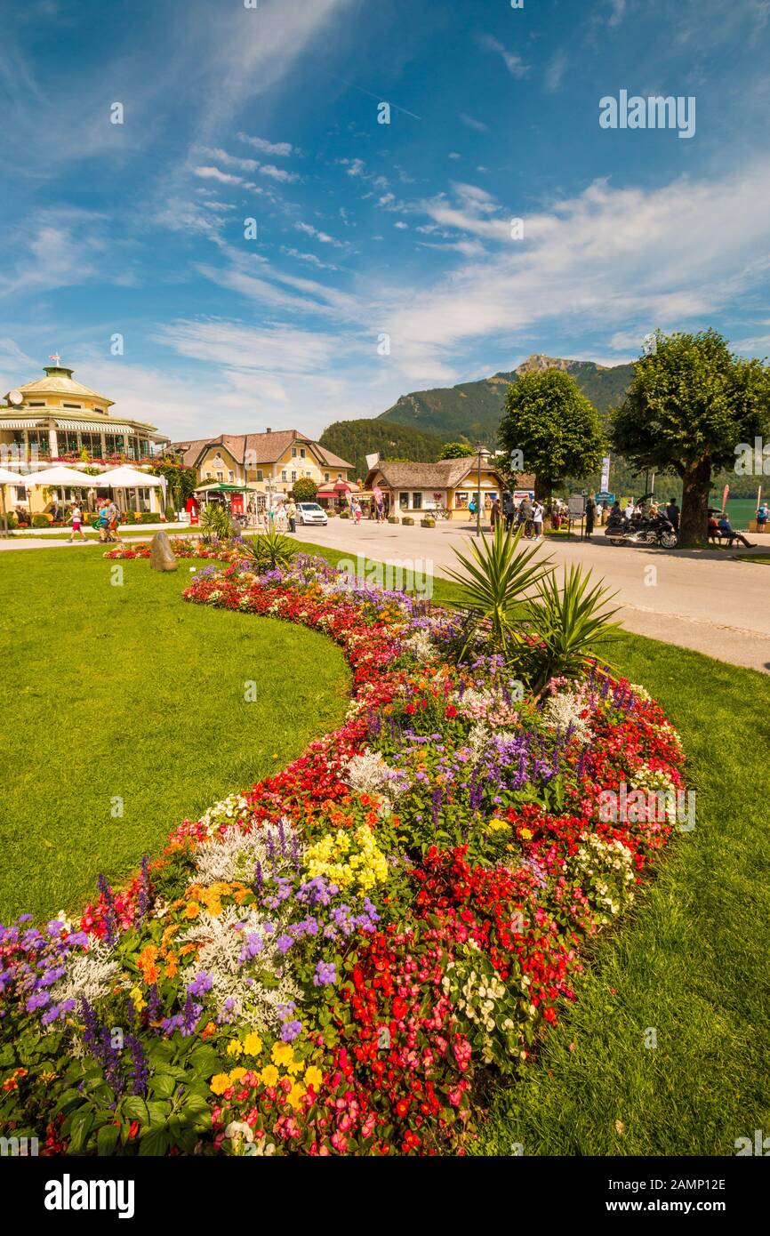 St.Gilgen, Austria - August 6, 2019: Park with beautiful flowerbed  and Wolfgangsee lake promenade full of tourists on a sunny summer day Stock Photo