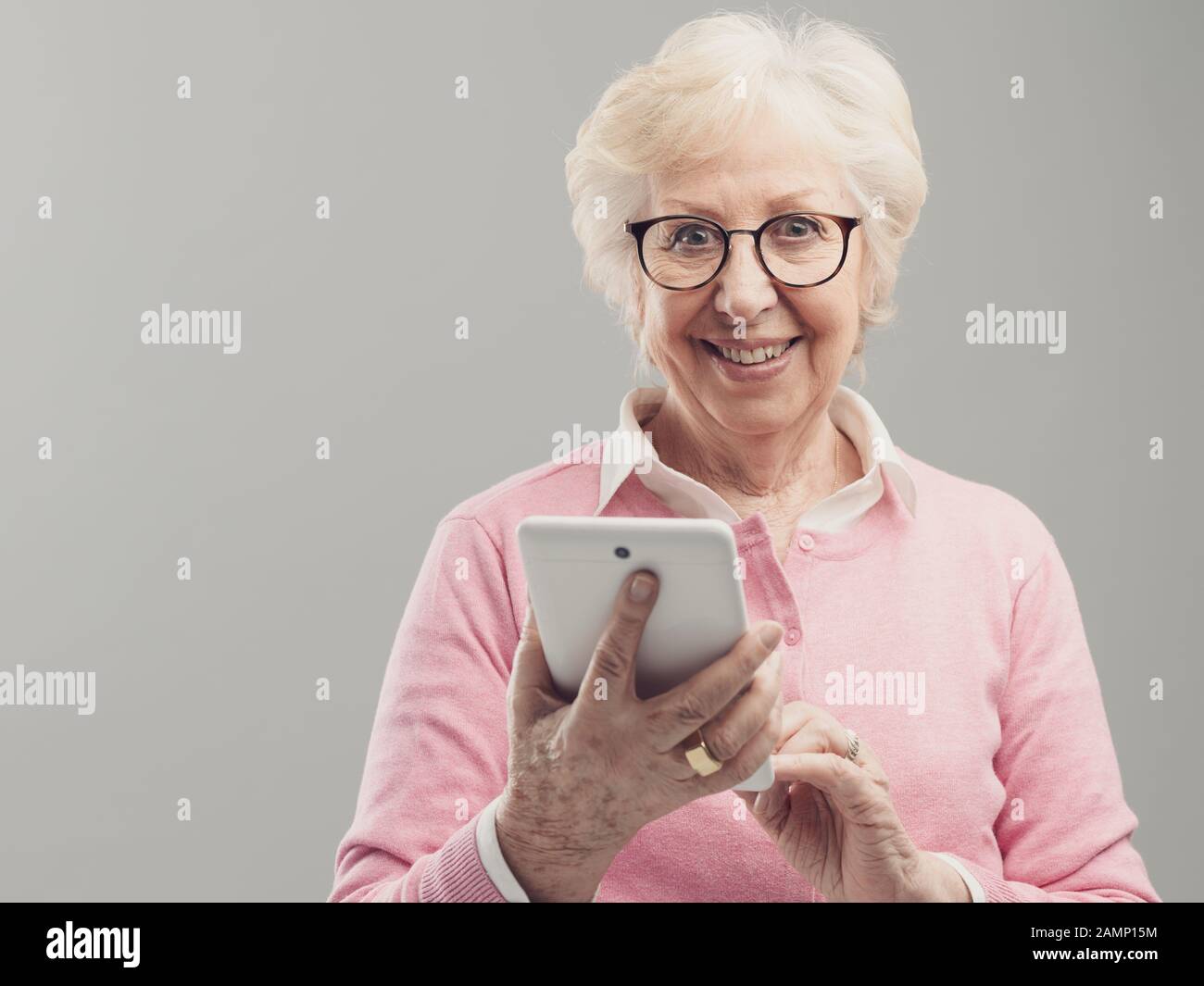 Happy senior lady using a digital touch screen tablet, she is