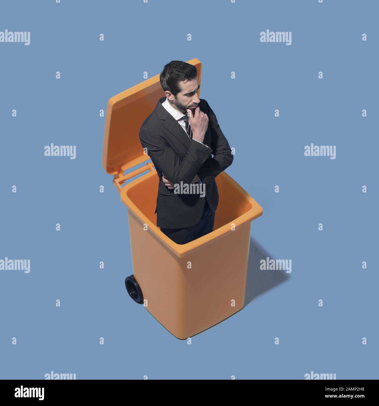 Disappointed corporate businessman standing in a trash bin, he has been discharged Stock Photo