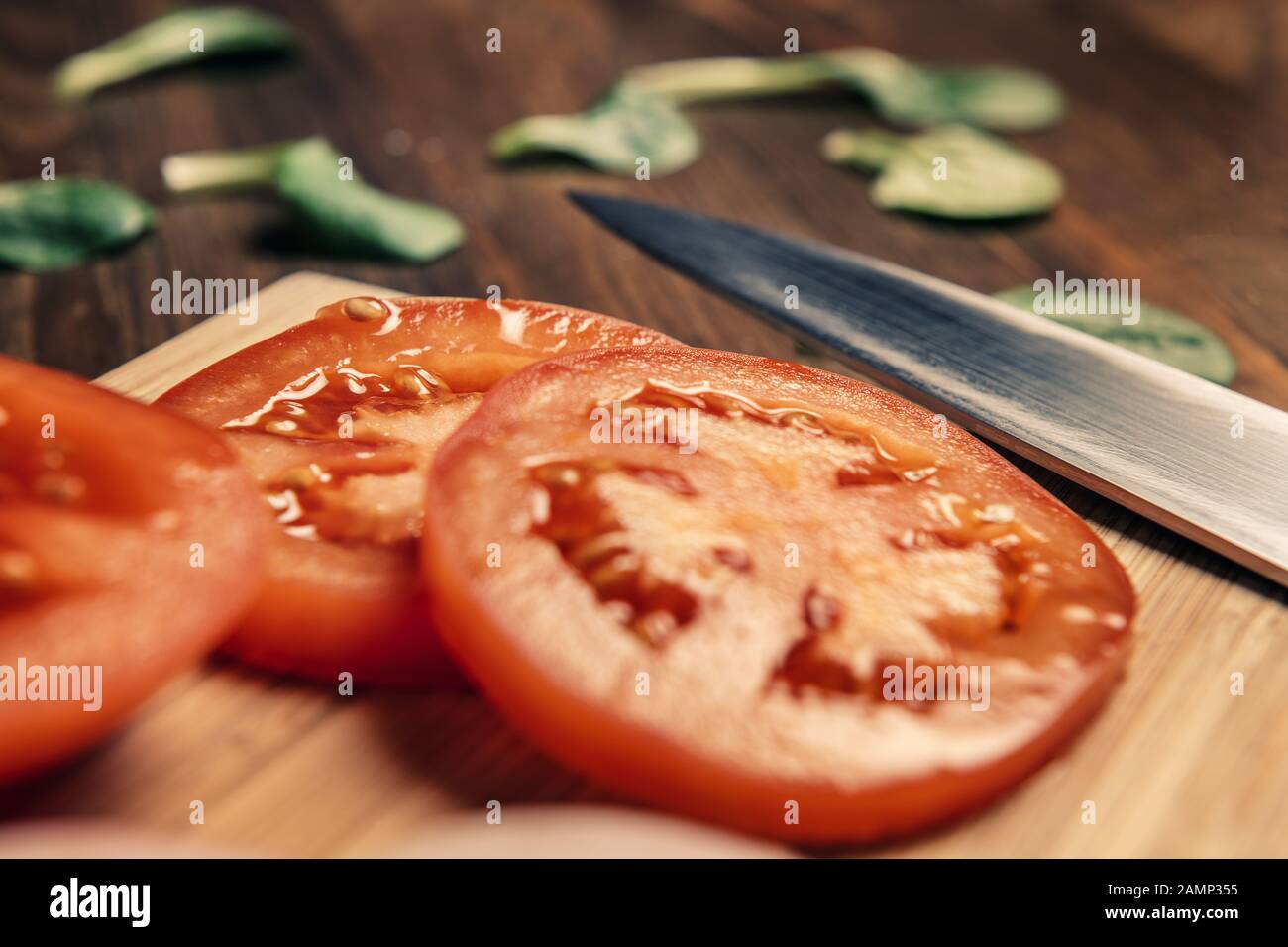 close up of tomato slices with a knife on a wooden cutting board, vegan food and healthy lifestyle concept Stock Photo