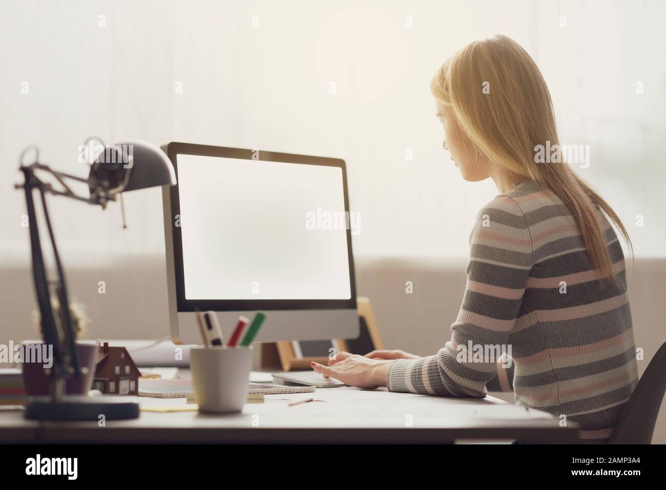 Young attractive woman sitting at desk and working with her computer ...