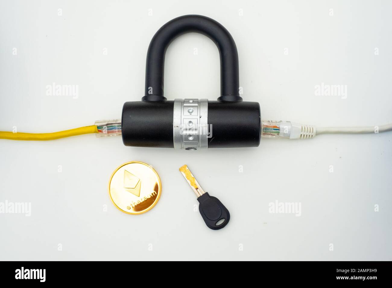Two computer network cables going through a lock with a key and a crypto currency coin