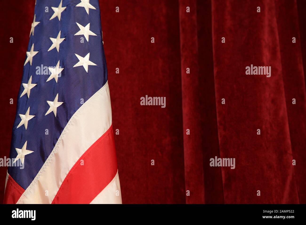 The American Flag pictured in front of red velvet curtains. Stock Photo