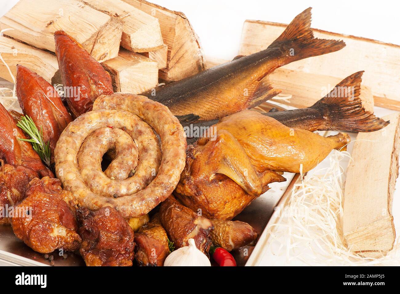 Smoked fish, poultry and sausages on a background with wood and sawdust Stock Photo