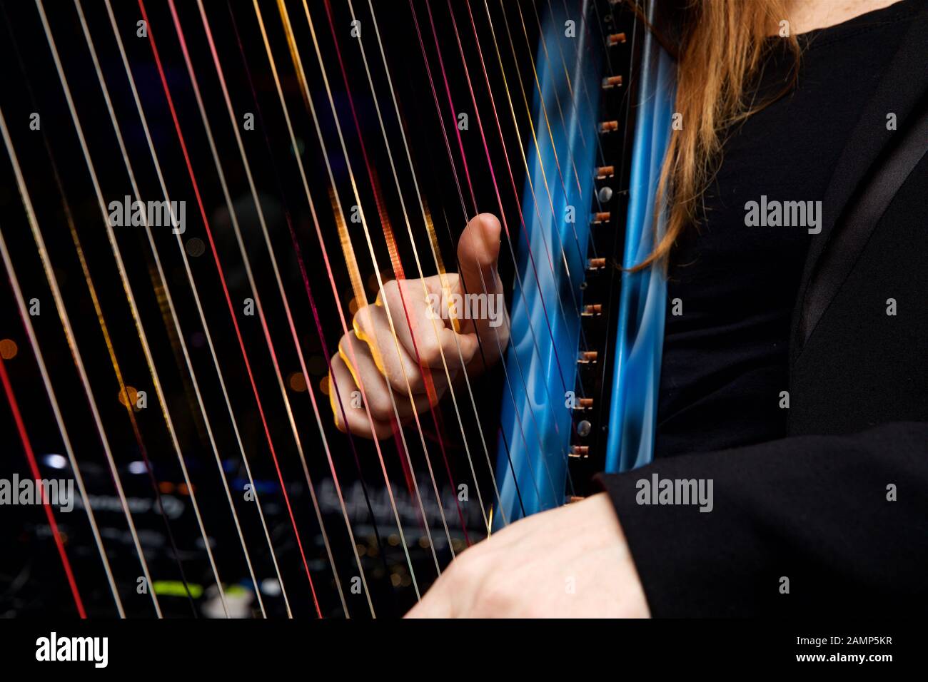 Close up shot of a woman playing a harp with multicoloured fibre optic lights embedded in the strings. Stock Photo