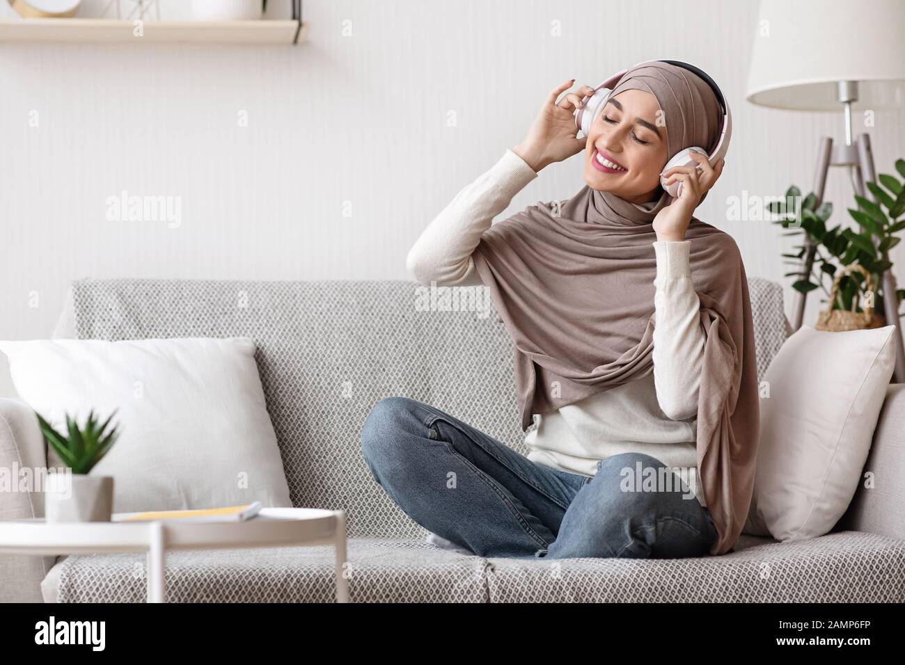 Relaxed Muslim Girl In Hijab Listening Music With Wireless Headphones