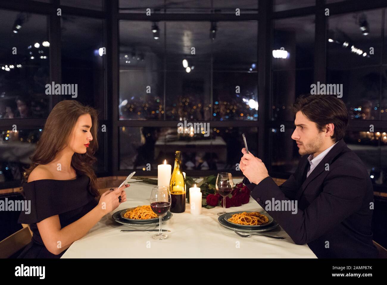 Man and woman chatting on cellphones, ignoring each other Stock Photo