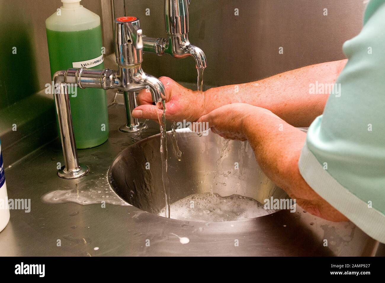 Female medical professional washing her hands at a sink. Stock Photo