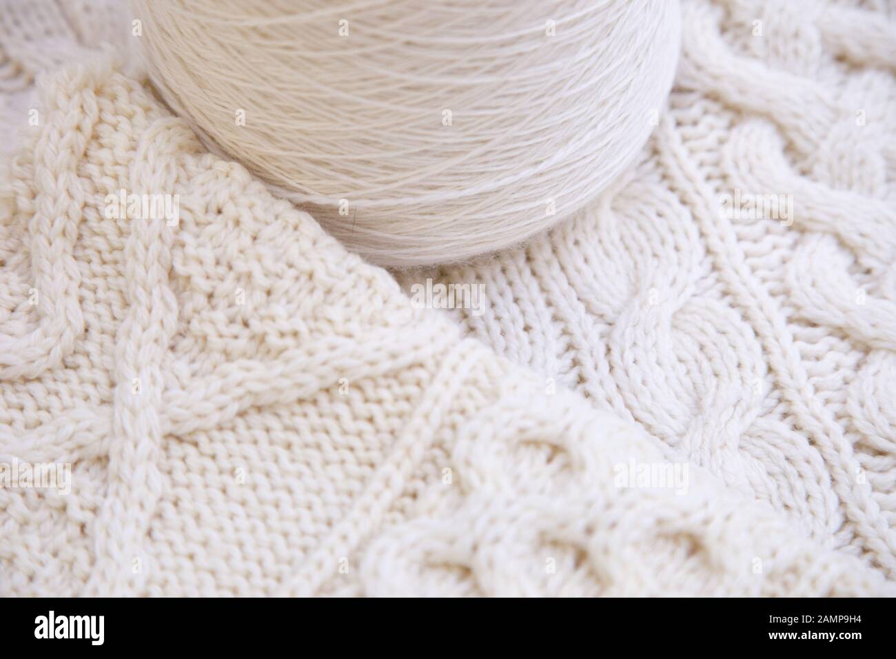Close up shot of the stitching on an Aran sweater beside a yarn of wool. Stock Photo