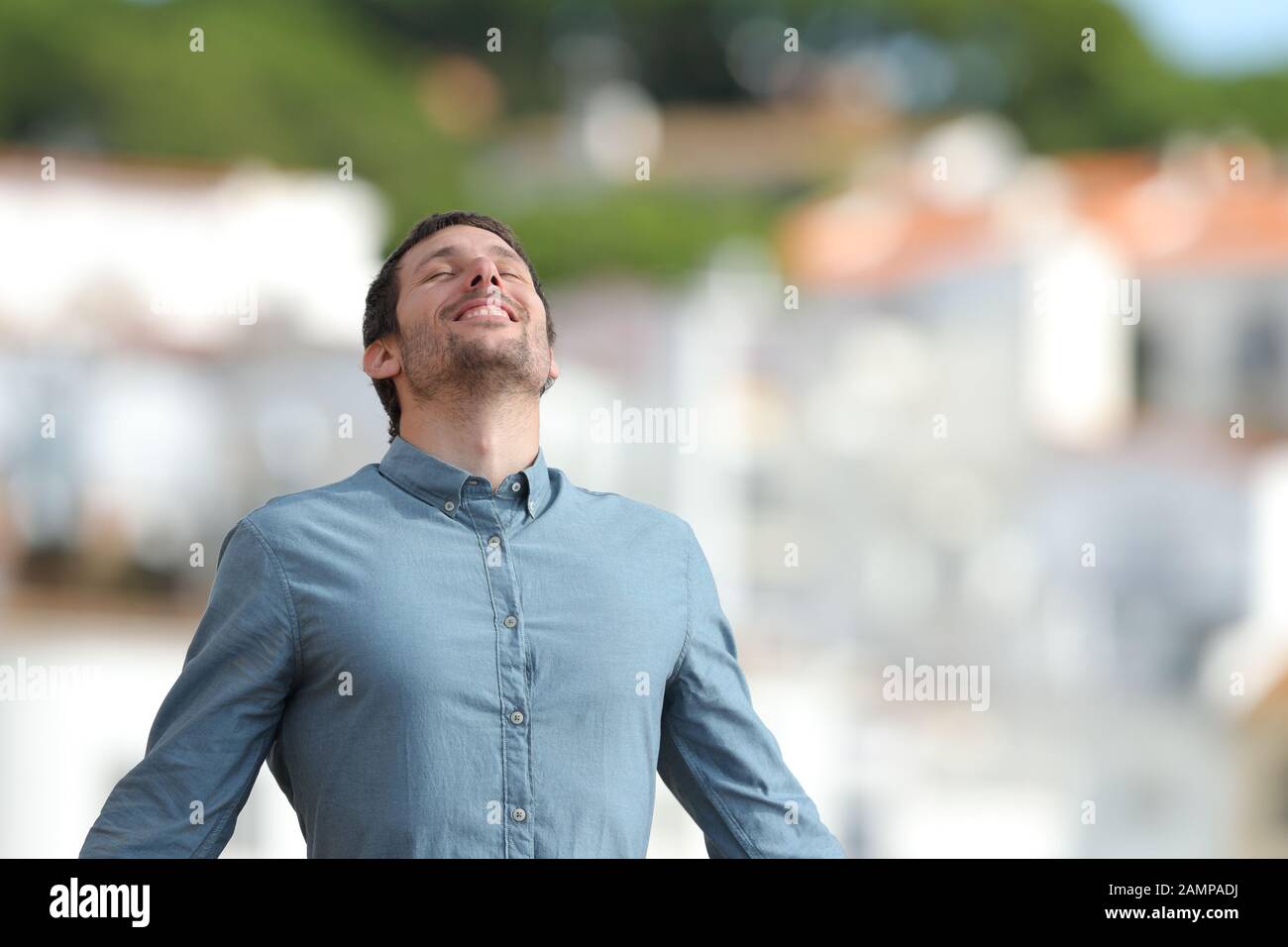 Happy adult man breaths deeply fresh air standing in a rural town a sunny day Stock Photo