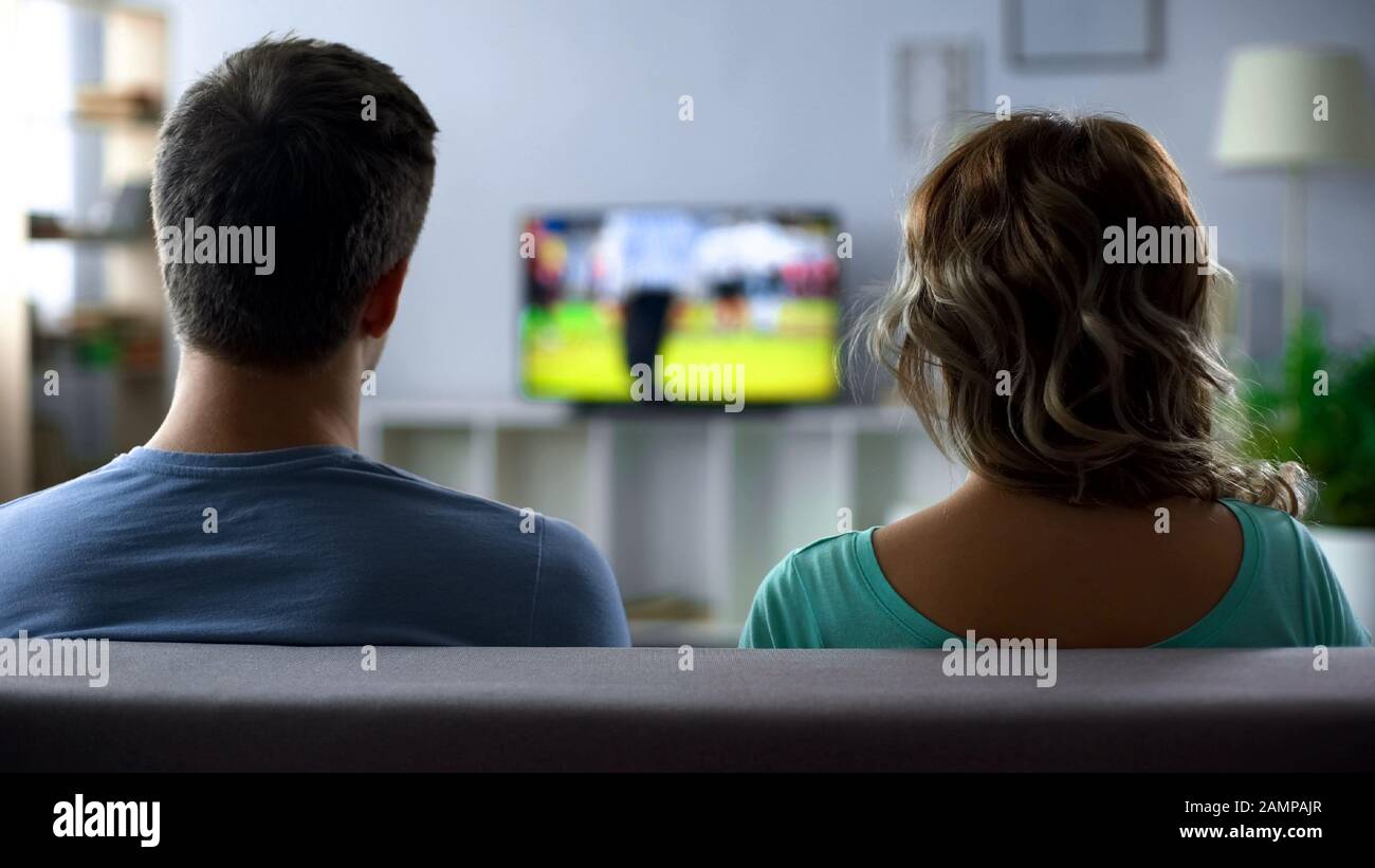 Bored couple watching football match on tv, conflict, passive pastime together Stock Photo