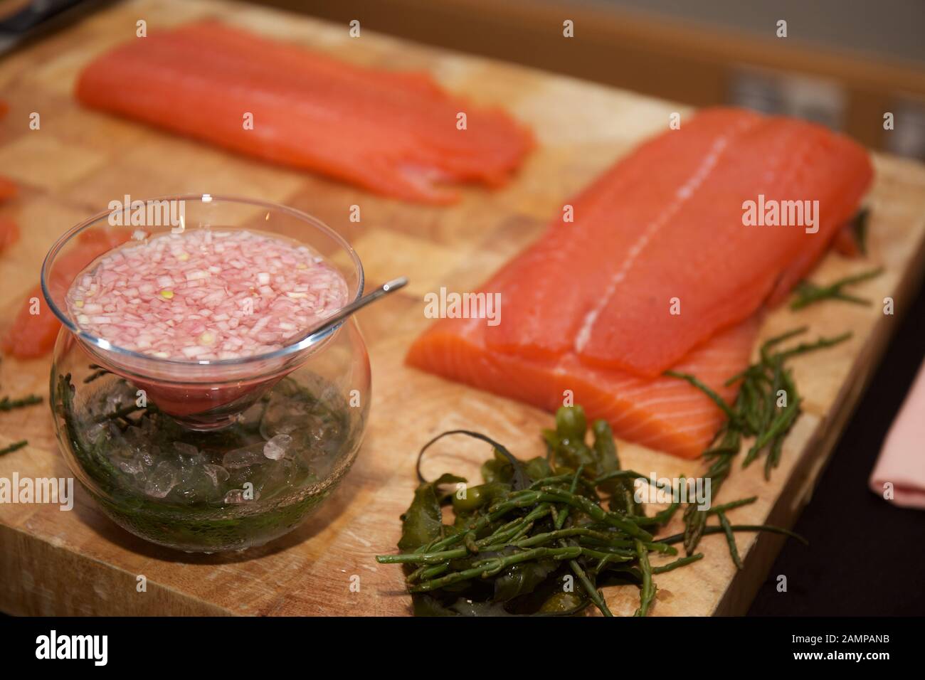 Preparing smoked salmon and seaweed on a wooden chopping board. Stock Photo