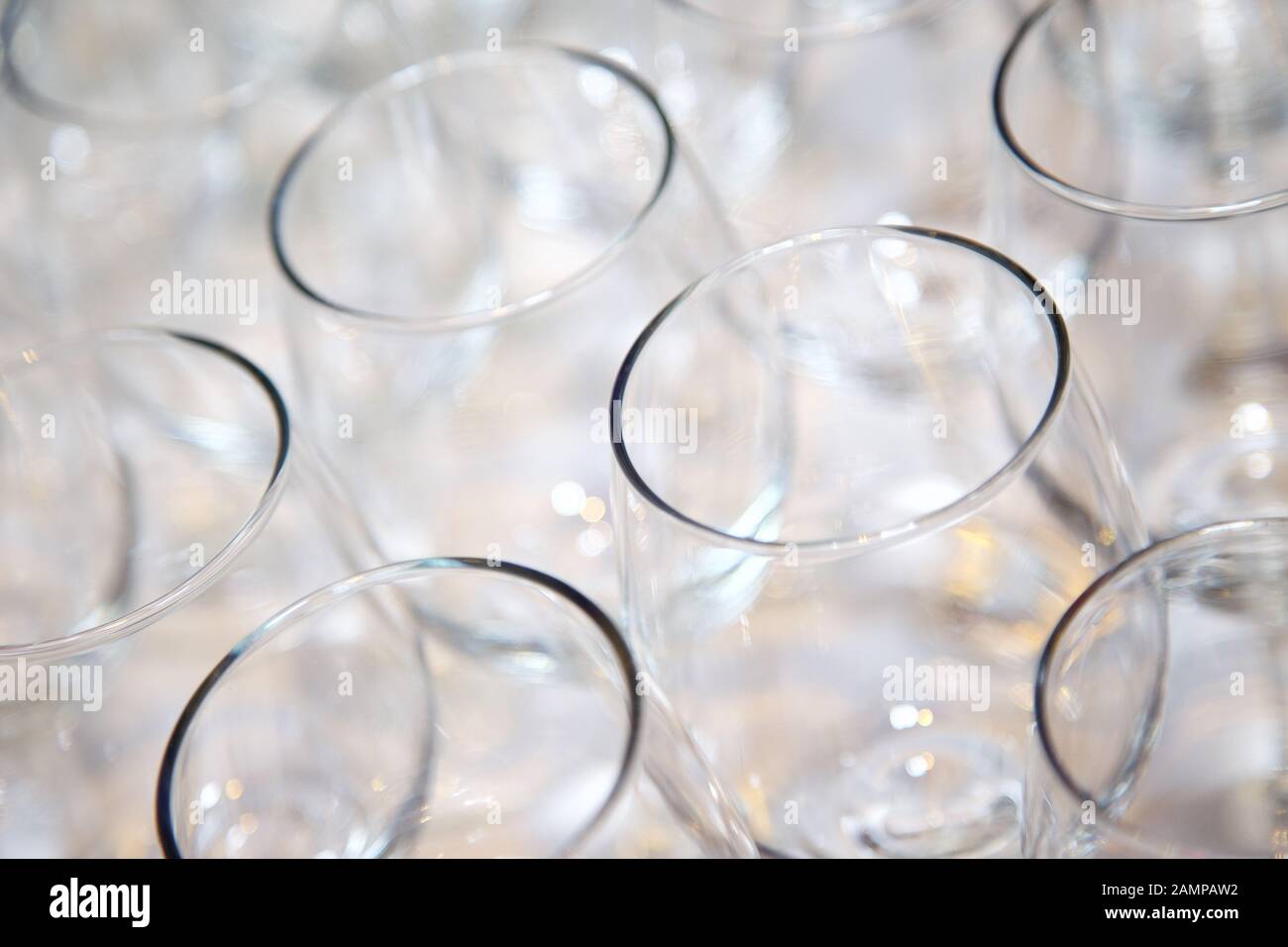 Collection of empty drinking glasses arranged on a bar or restaurant counter. Stock Photo