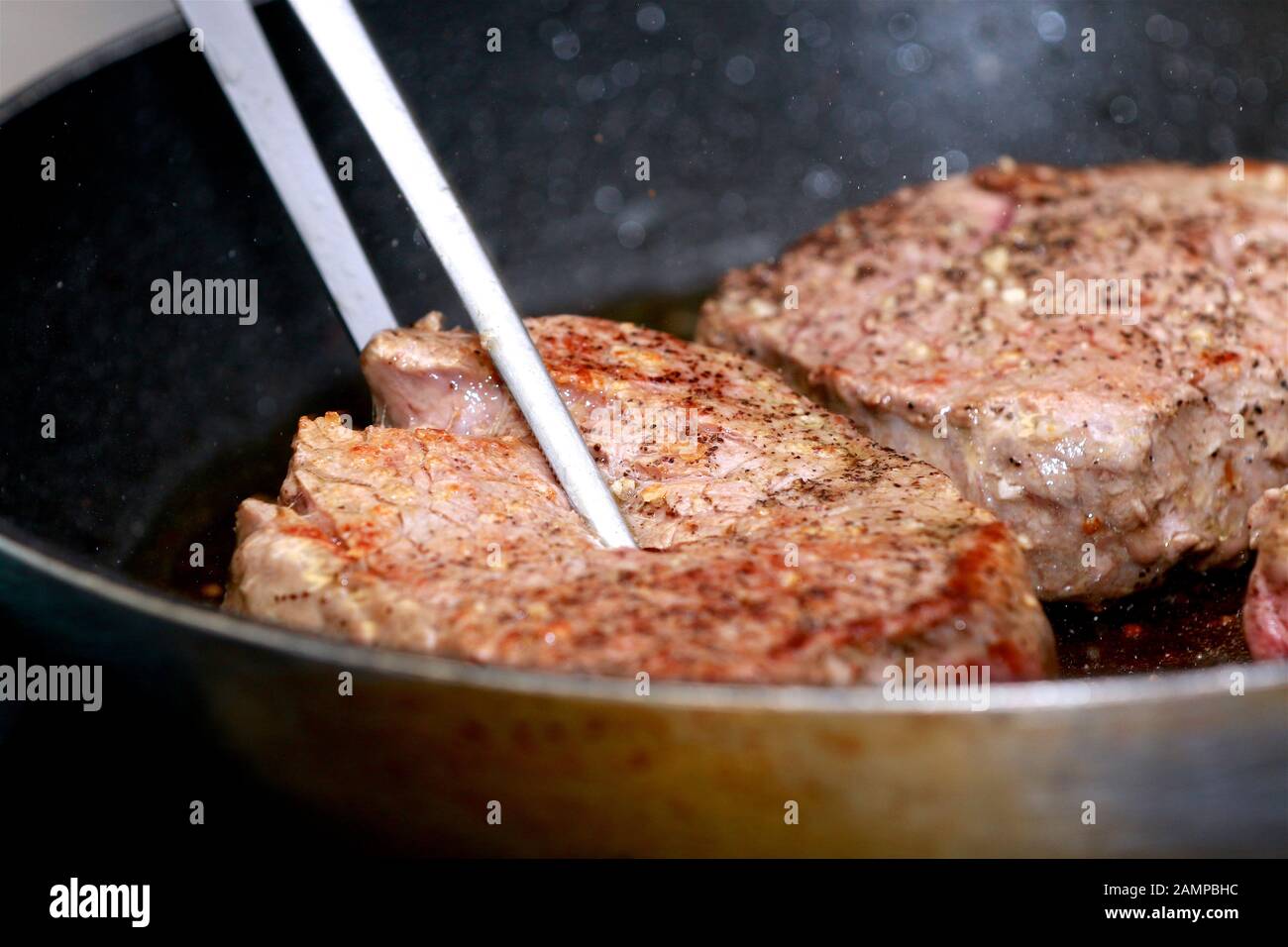 Cooking seasoned fillet beef steak in a frying pan. Stock Photo