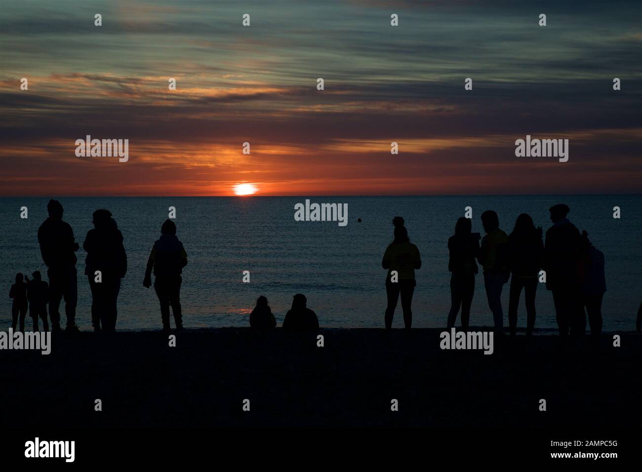 A group of people in silhouette on a beach in County Wicklow at sunset on the east coast of Ireland. Stock Photo