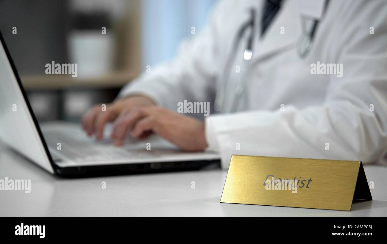 Male dentist filling out medical form in hospital, prescribing