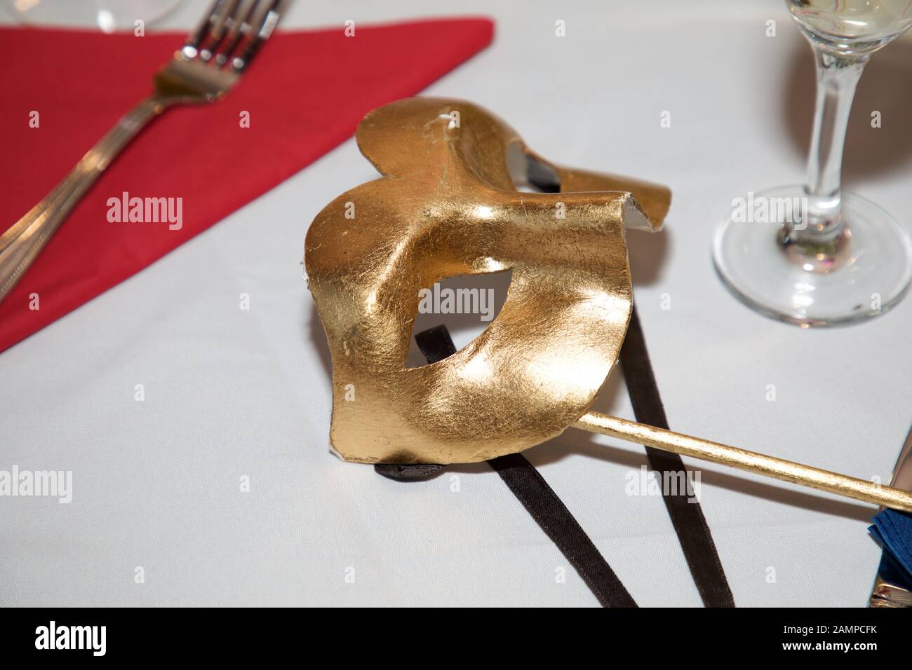 A golden masquerade ball mask on a dinner table. Venetian Eye Mask carnival, Fancy Dress Accessory, Carnival Party Costume Ball. Stock Photo