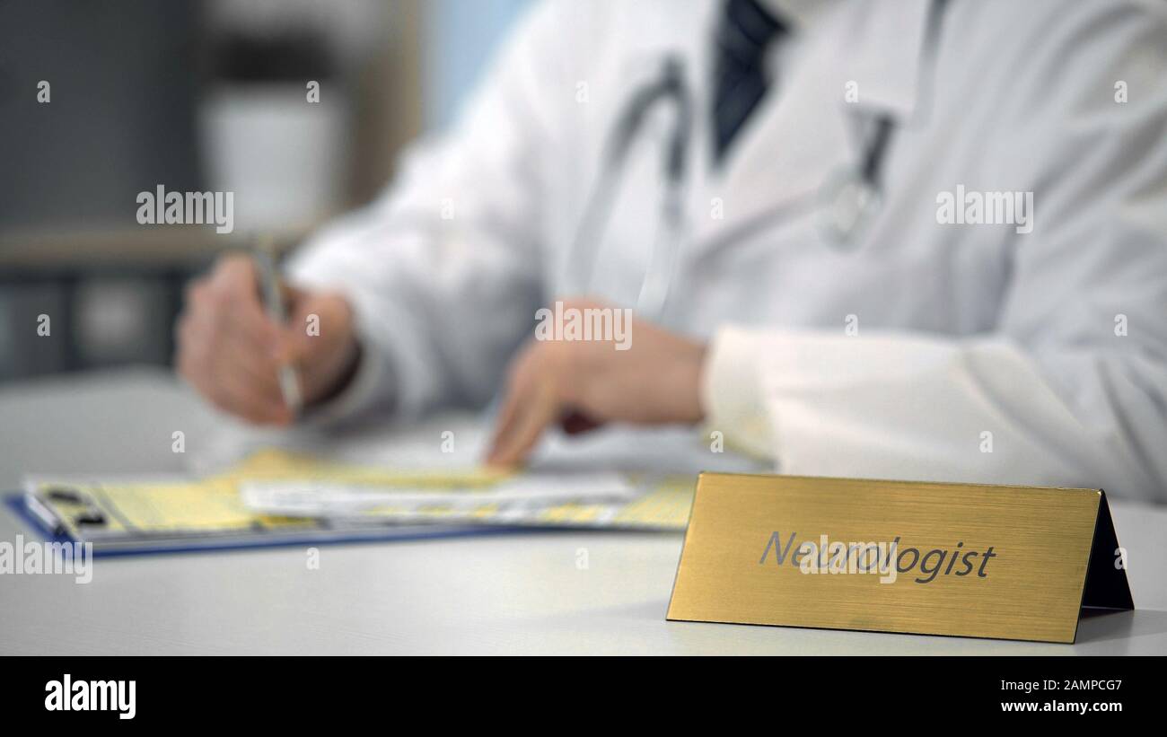 Male neurologist in uniform typing on laptop in clinic, keeping medical records Stock Photo