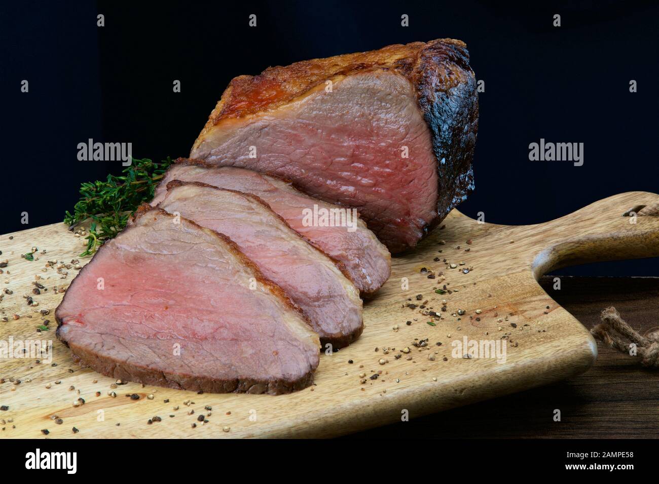 Close-up shot of a joint of juicy roast beef sliced on a wooden platter. Stock Photo