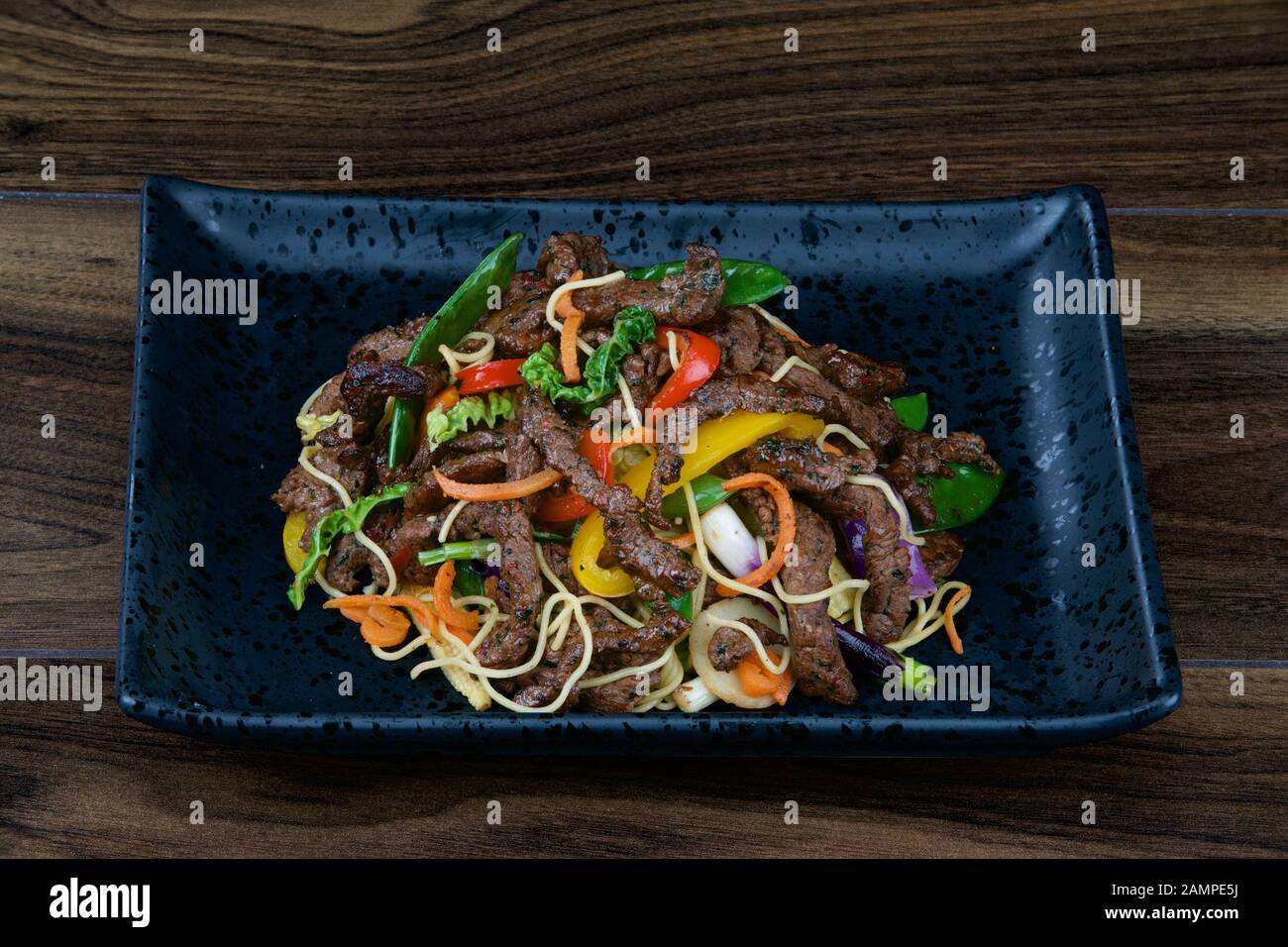 Asian stir fried beef served with noodles and vegetables. Stock Photo