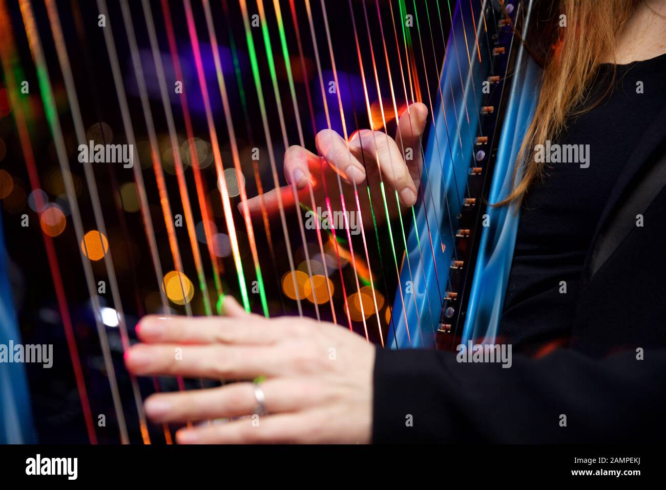 Close up shot of a woman playing a harp with multicoloured fibre optic lights embedded in the strings. Stock Photo