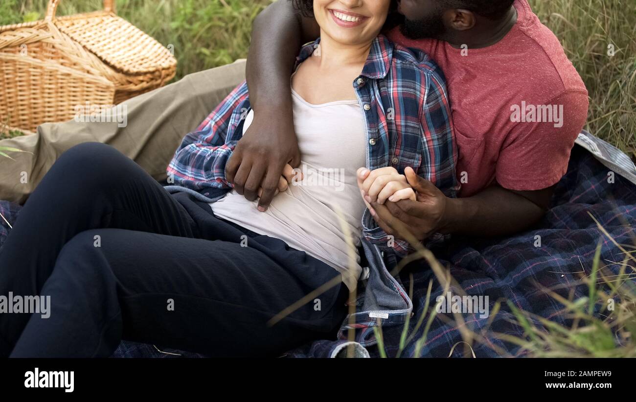 Joyful husband hugging pregnant wife outdoors, future parents relaxing in nature Stock Photo