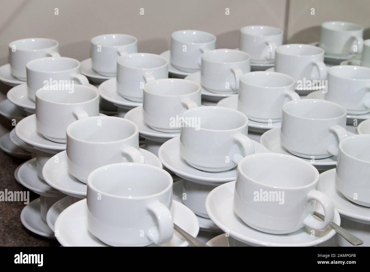 Rows of stacked cups and saucers ready for service. Stock Photo