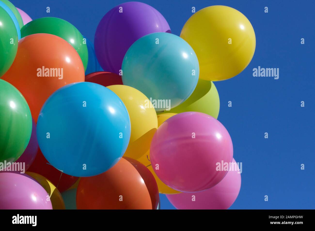 Multi-coloured party balloons pictured against a blue sky. Stock Photo