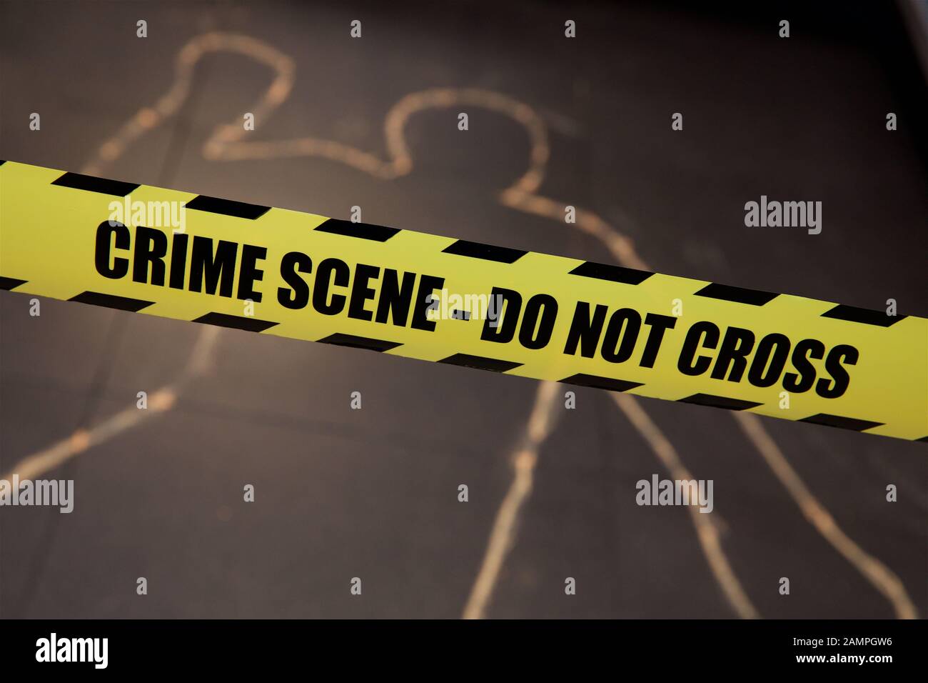 Mock crime scene with yellow police cordon ribbon and chalk body outline. Stock Photo