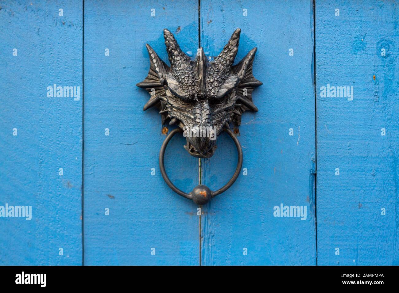 Ornate metal door knocker in the shape of a dragon's head holding the ring in it's mouth Stock Photo