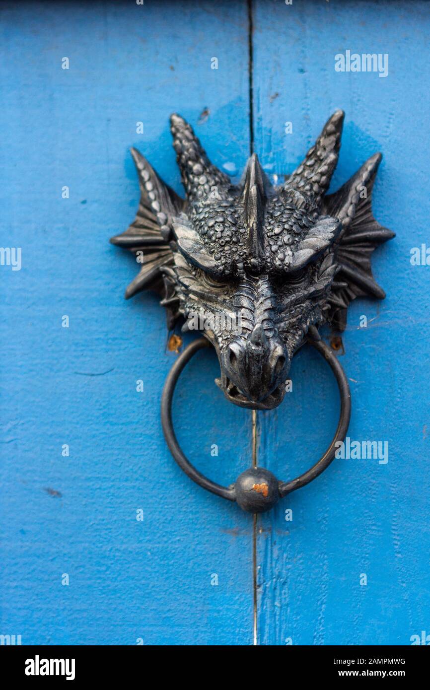 Ornate metal door knocker in the shape of a dragon's head holding the ring in it's mouth Stock Photo