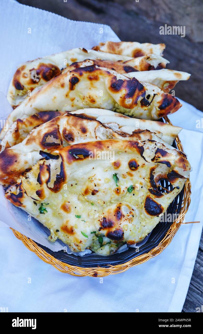 A basket of hot garlic naan bread at an Indian restaurant Stock Photo