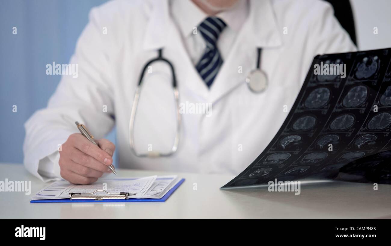 Doctor prescribing medication for brain disease, examining MRI scan, insurance Stock Photo