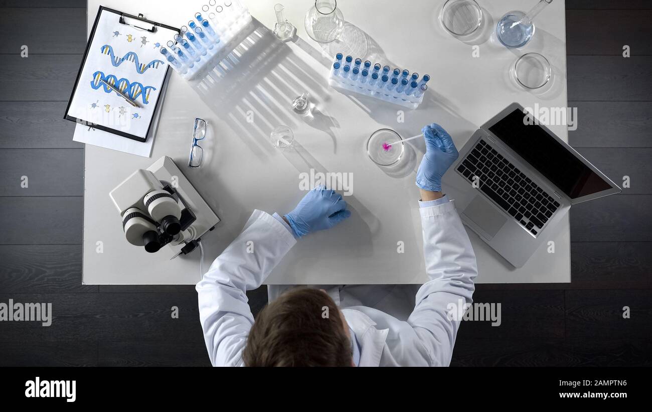 Lab researcher watching chemical reaction by adding reagent into special liquid Stock Photo