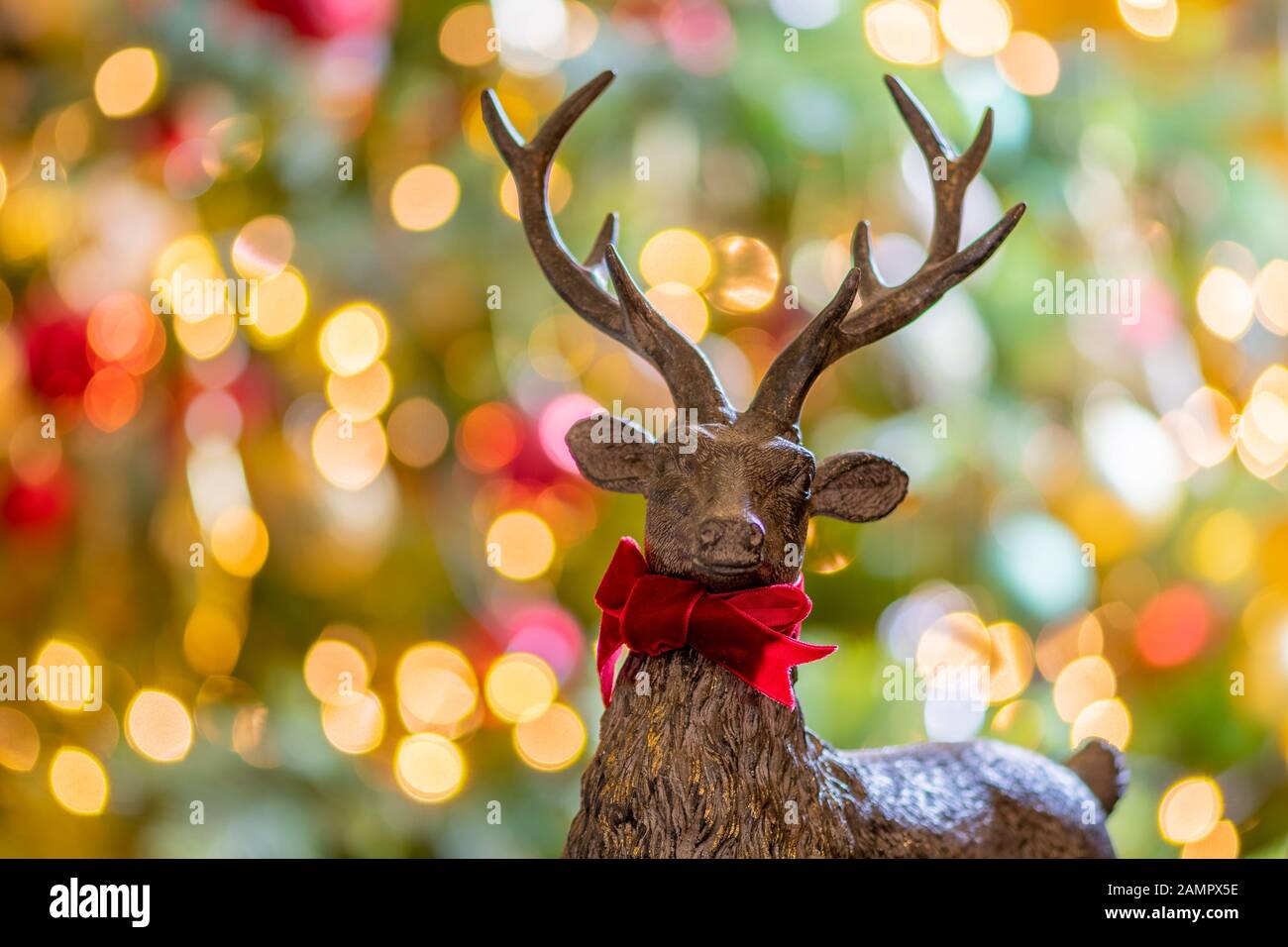 Close up of a wooden deer shaped christmas decoration with defocused fairy lights in the background Stock Photo