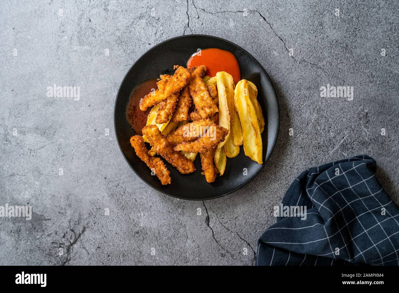 Fish and Chips made with Breaded and Fried Seabass in Black Plate. Fast Food. Stock Photo