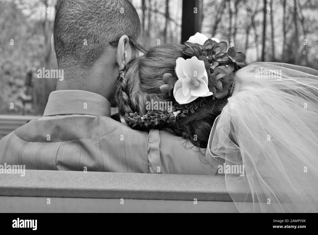 Young bride and groom cuddling on a bench on their wedding day Stock
