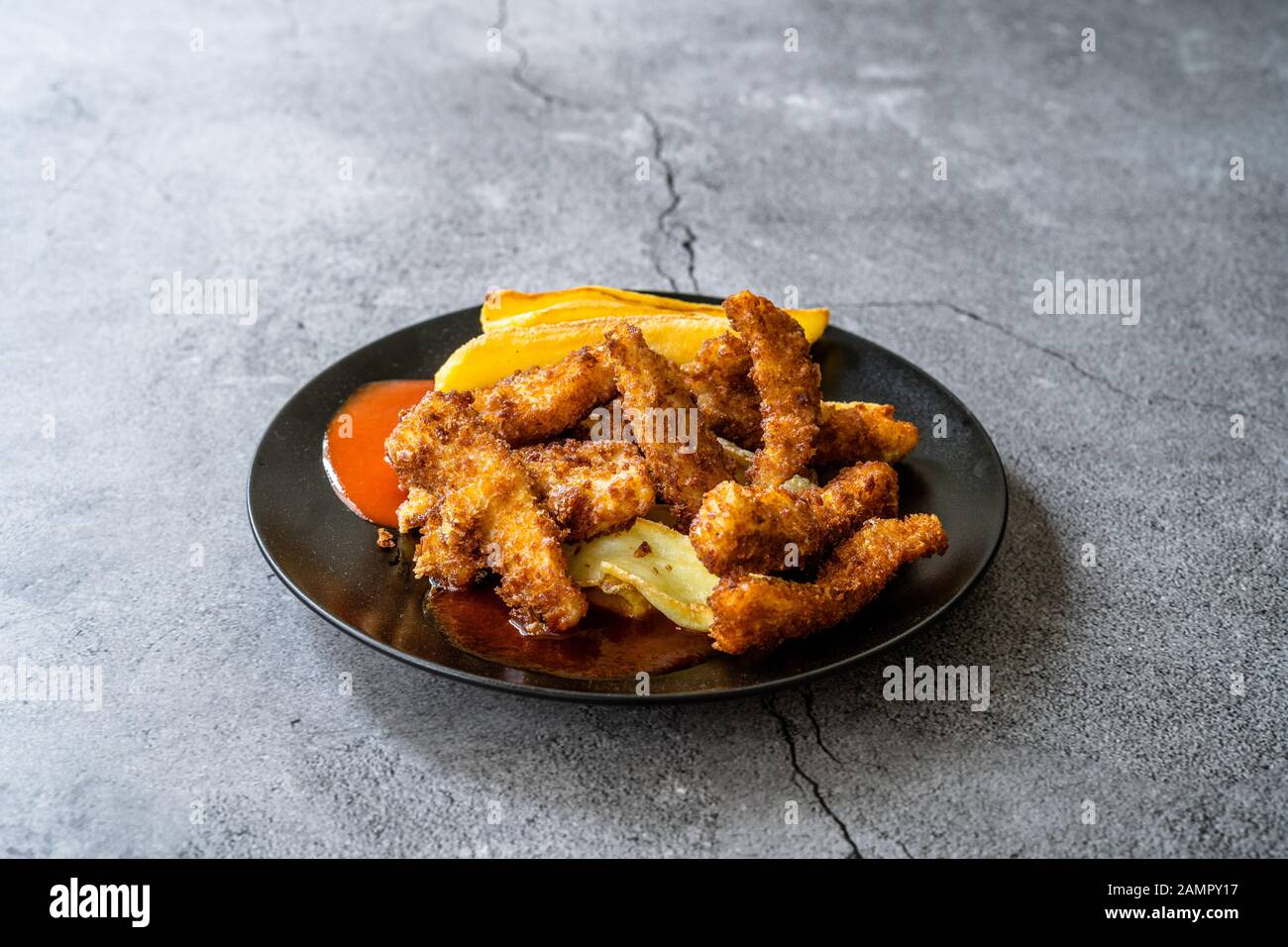 Fish and Chips made with Breaded and Fried Seabass in Black Plate. Fast Food. Stock Photo