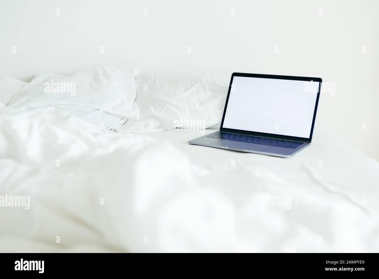 laptop with copy space empty screen at bed with white sheets Stock Photo
