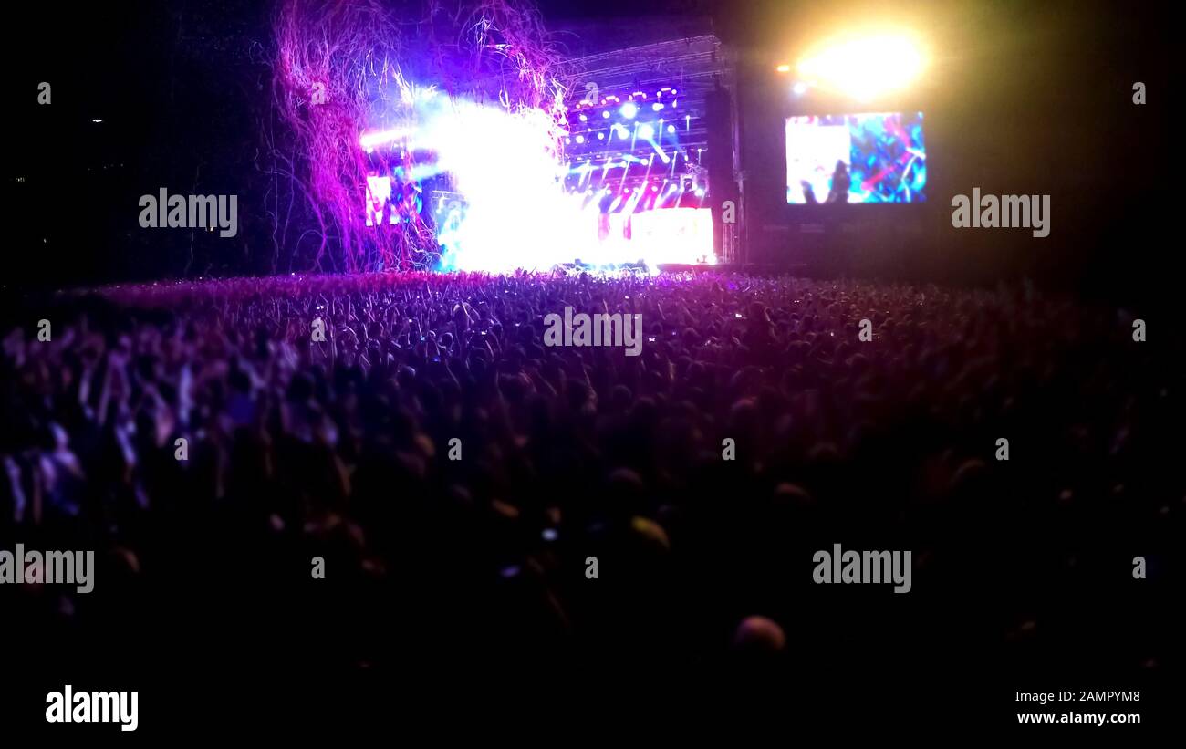 Concert stage with crowd of people standing in front, performance at