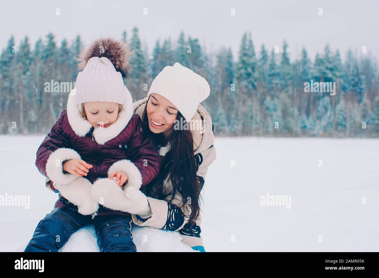 Happy family of mom and little kid playing snowballs in the winter ...