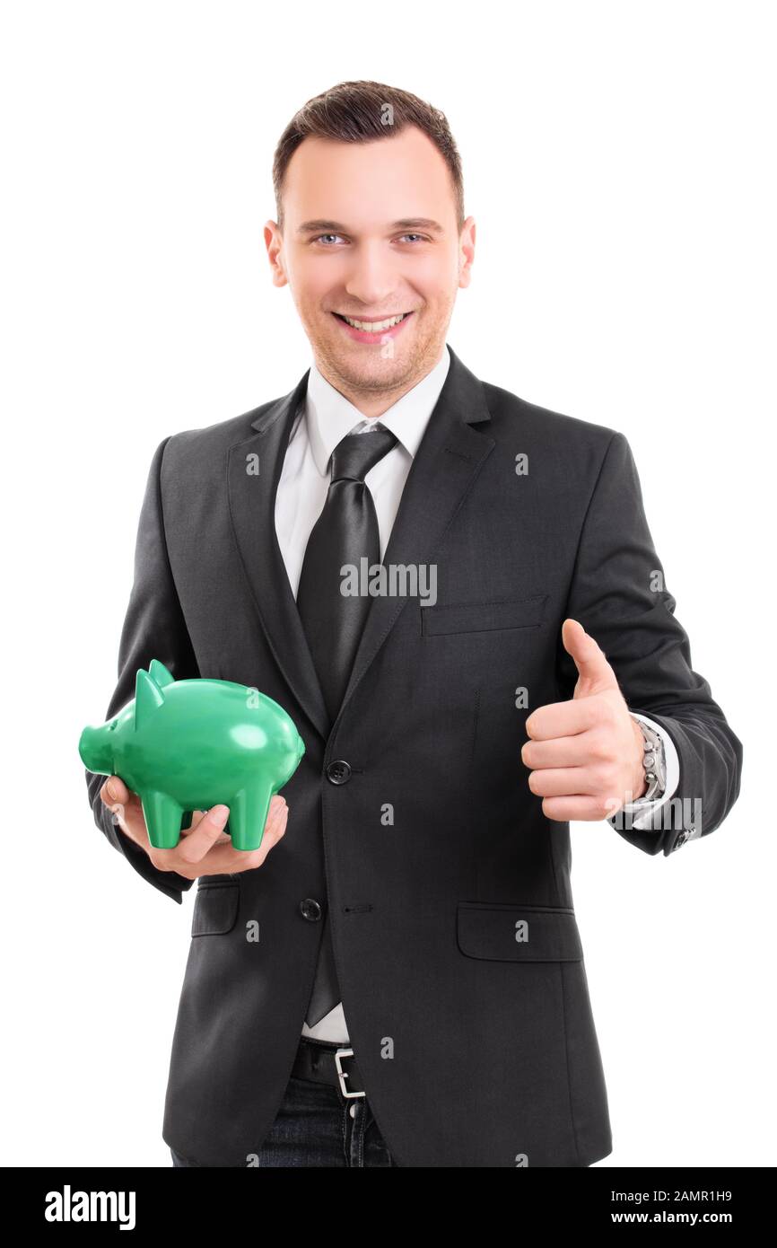 Handsome young businessman in a suit holding a piggy bank, smiling and ...