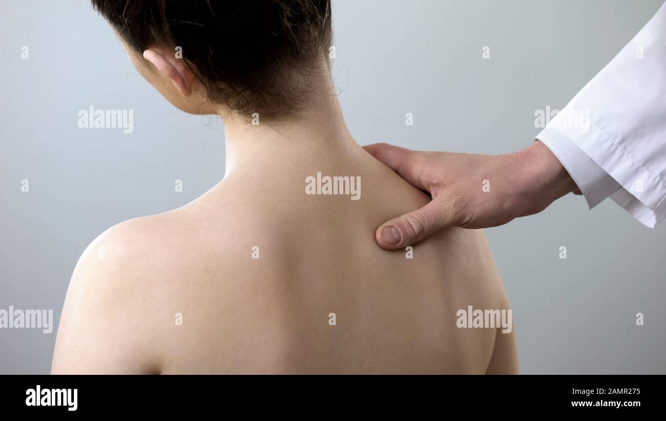 Specialist examining female back, holding her shoulder, scoliosis treatment Stock Photo