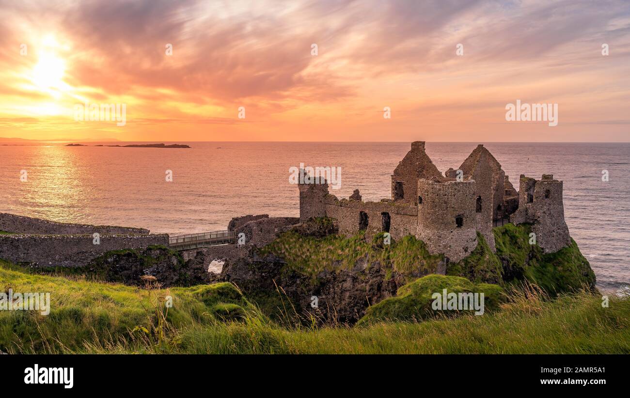 Ruined medieval Dunluce Castle on the cliff in Bushmills, Northern Ireland at sunset. Filming location of popular TV series, Game of Thrones Stock Photo