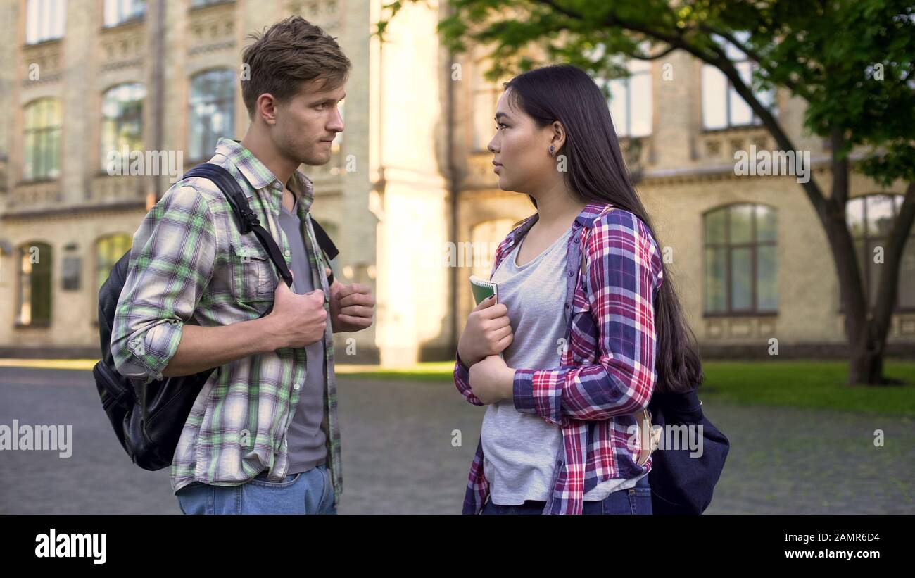 Young man communicates with geek girl student, asks for help in exam preparation Stock Photo