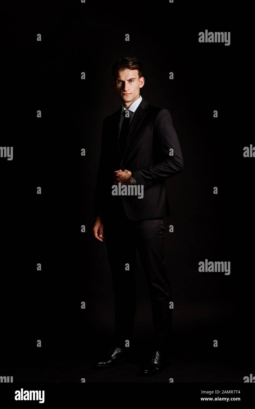 handsome businessman in suit standing isolated on black Stock Photo